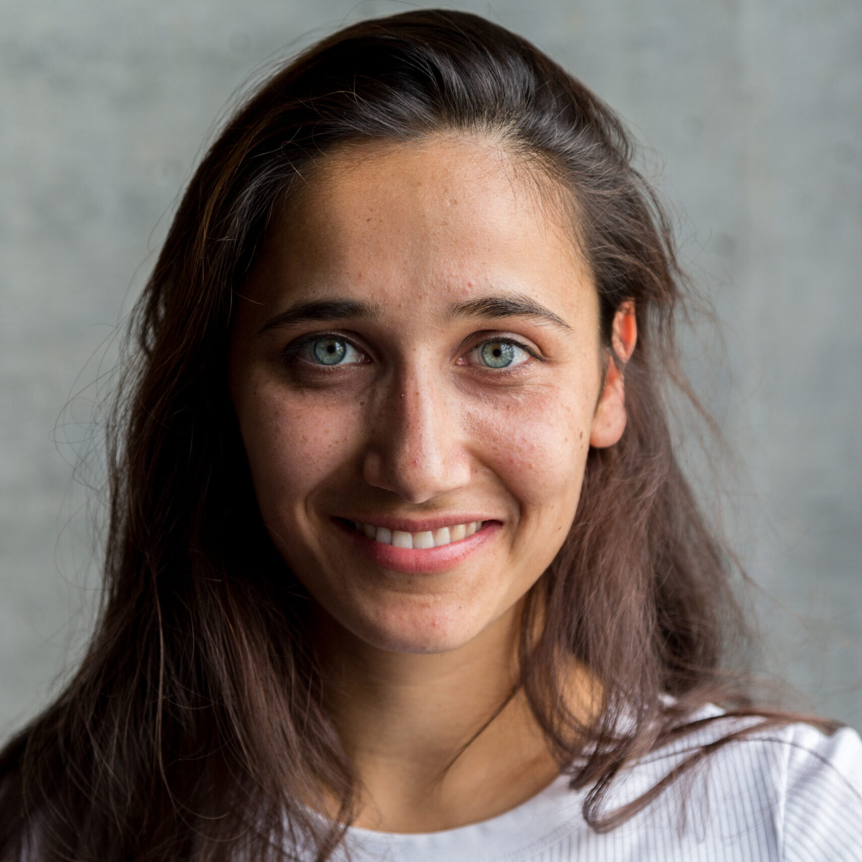 Pretty middle eastern woman with light colored eyes smiling. Close up. Looking at camera.